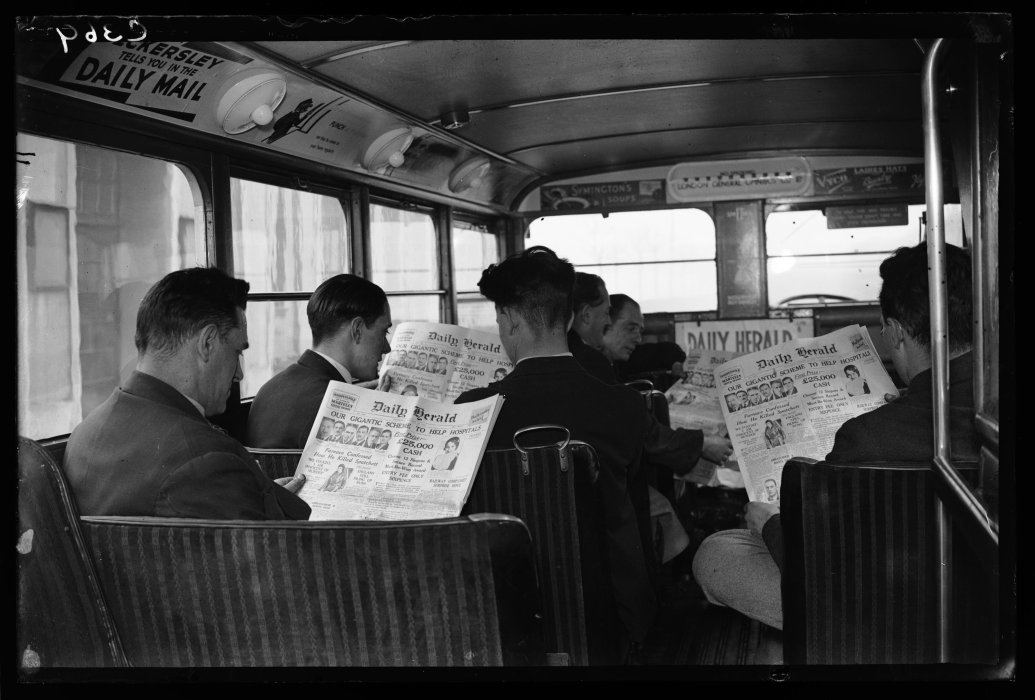 Passengers on a London General Omnibus reading the front page of the Daily Herald