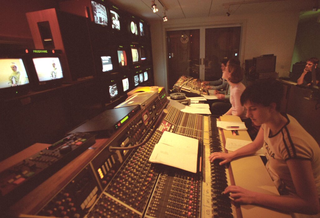 A photograph of people sitting in front of mixing desk