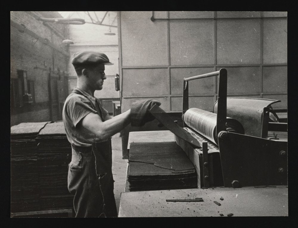 A worker feeds shellac through heated rollers
