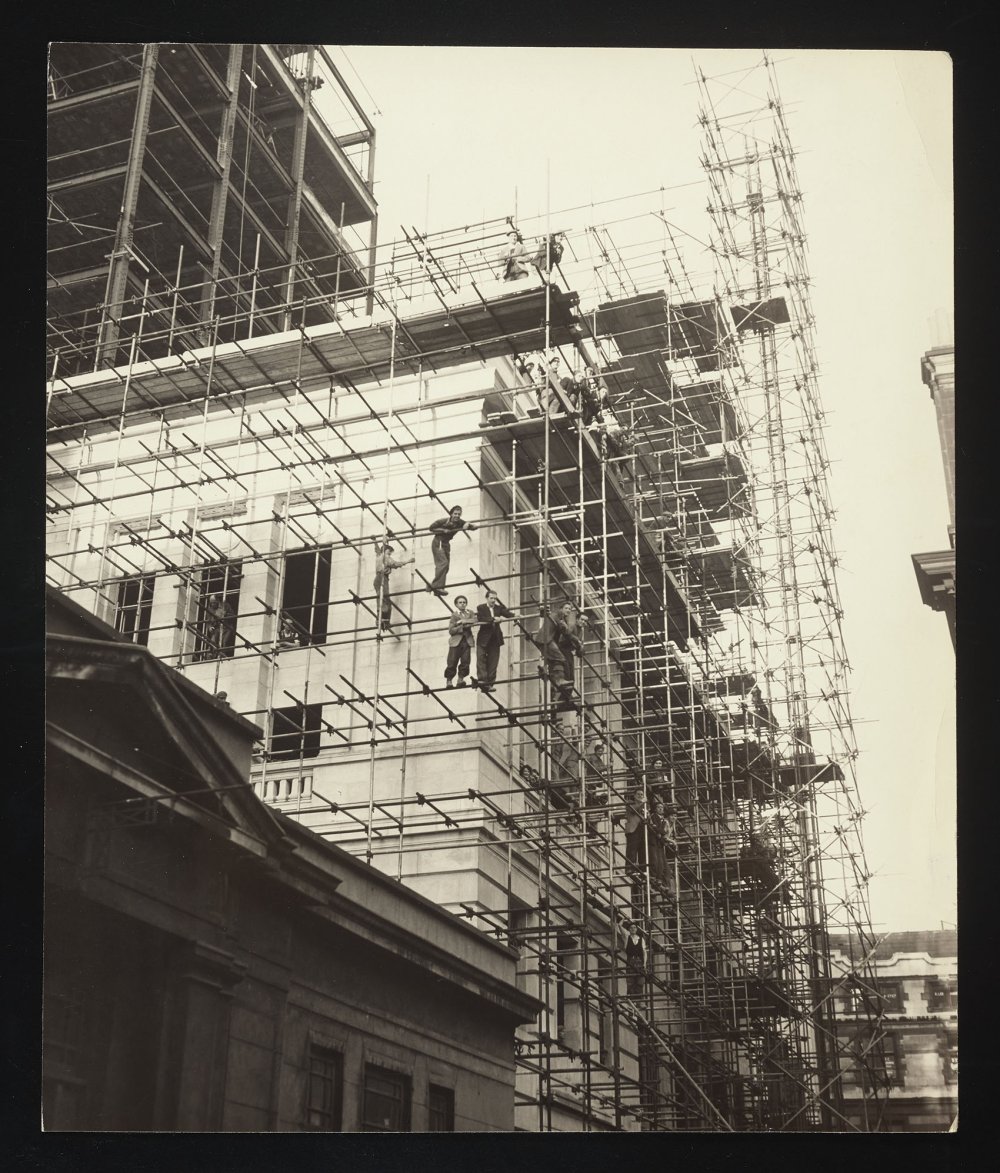 Workers looking down from scaffolding on a building