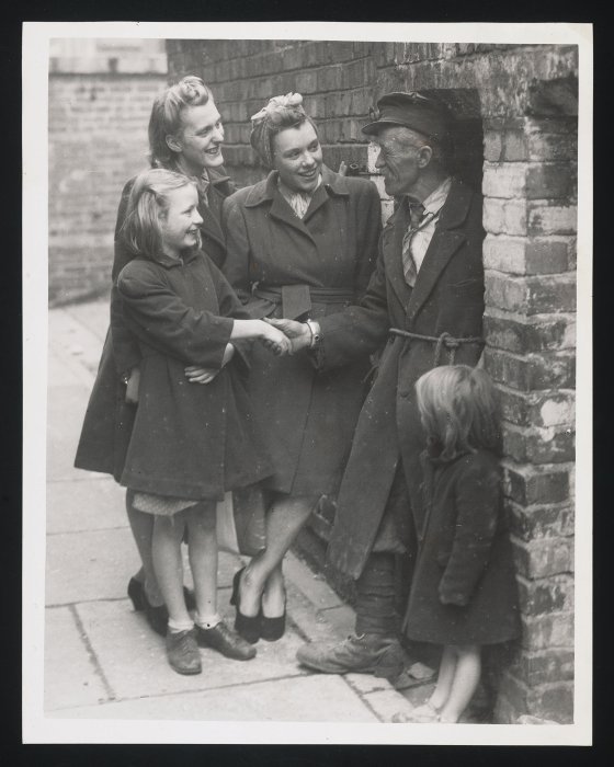 Man talking to three women outside air raid shelter
