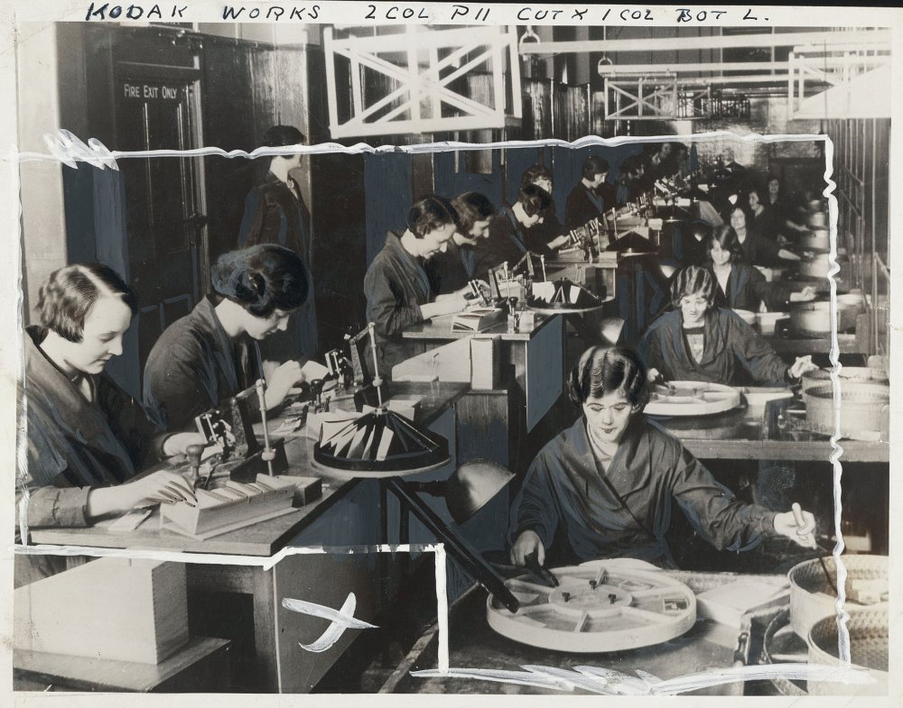 View of numerous workers in a camera factory