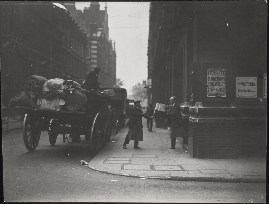 Newspapers being loaded onto horse-drawn wagons in a London street