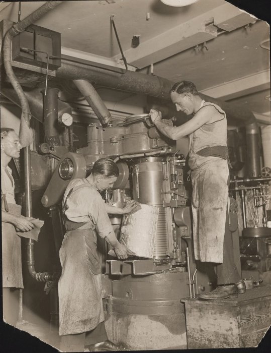 Three workers casting plates in a foundry