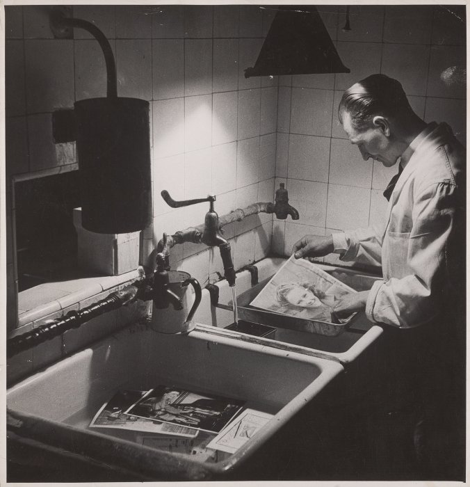 A man developing photographs in a darkroom